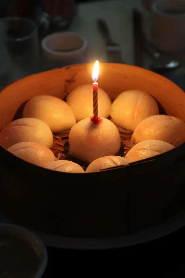 侍者将厢房的灯光突然调暗,其后奉上点上蜡烛的寿包,更一起唱上生日歌