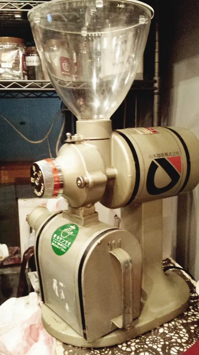 這部懷舊風的磨豆機是老闆最近BID 回來的心頭好。日本原廠已不再出產。其低溫磨豆的雙刀片設計，讓豆豆的品質傷害減至最低。勁HIT的台灣小飛馬磨豆機設計也是沿襲於它。