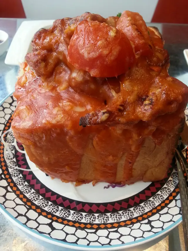 磚頭=方飽。把豬扒和西芹雞蛋炒飯放在挖空了的麵飽磚內,上面加蕃茄淋上蕃茄醬和芝士再焗。