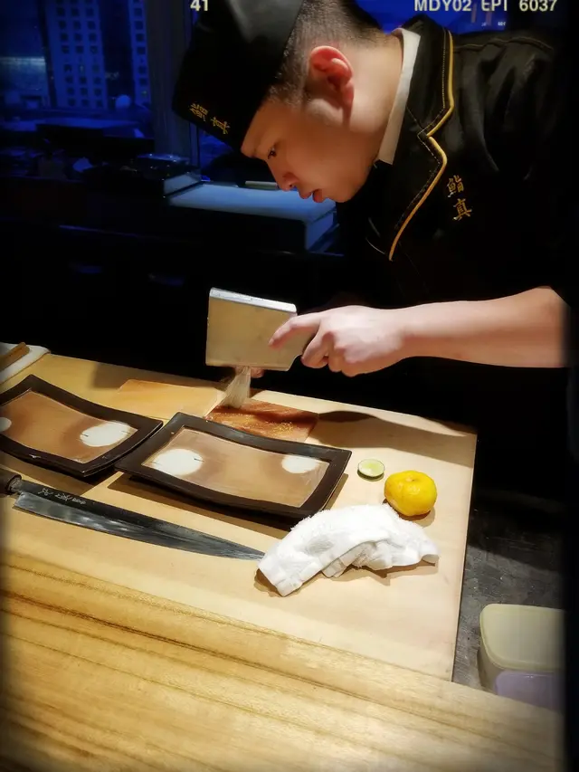 師傅仔喺兩塊粉紅板上掃上柚子粉末