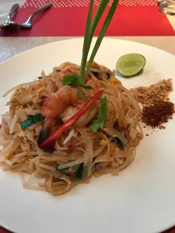 Pad thai stir-fried rice noodles with dried shrimp, tofu, bean sprouts & crushed peanuts with grilled tiger prawns