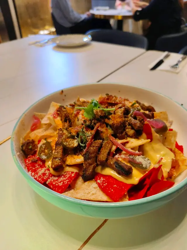 墨西哥粟米片上面鋪滿咗香噴噴嘅豬肉，還有新鮮嘅蔬菜同埋濃郁嘅芝士。份量超大，三個人分享都覺得好滿足。粟米片脆脆嘅，同豬肉嘅香味完美結合，每一口都好開心。